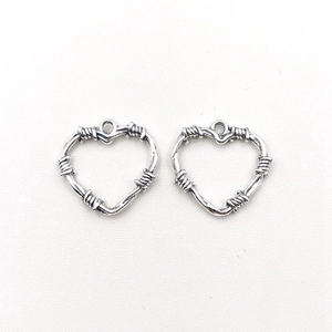 Close-up of two silver thorn heart charms for DIY necklace and earring jewelry making