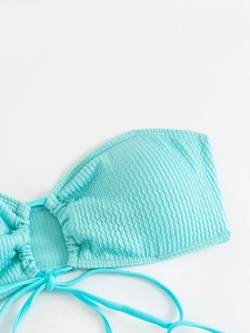 Detailed macro shot of light blue ruched bikini top texture with stylish side ties