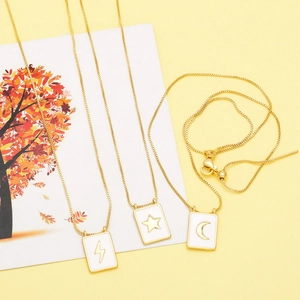 Detailed macro view of three gold-plated necklaces with enamel star, moon and lightning charms