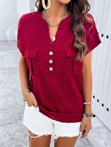 Detail of red V-neck blouse featuring jacquard dots, front buttons and chest pockets