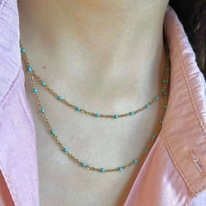 Close-up of double-layer gold titanium steel necklace with blue beads on a model