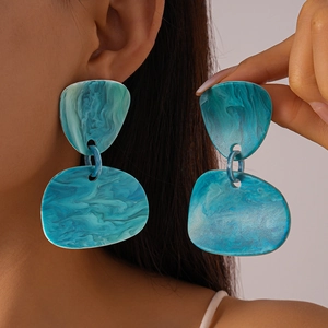 Macro detail of teal marble resin earrings with irregular geometric flat design