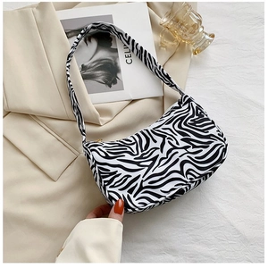 Detail of zebra print underarm bag on a beige blazer with fashion magazines