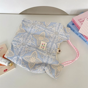 Detailaufnahme der Schmetterlingsstickerei und rosa Karogriff an hellblauer Stepp-Tragetasche