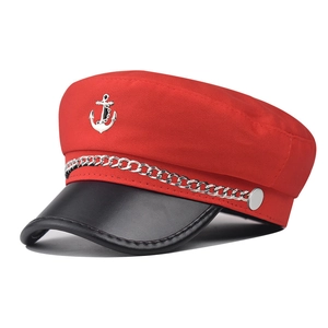 Detail of red sailor hat showing silver anchor emblem and thick chain on black visor