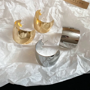 Macro shot of large polished C-shaped hoop earrings in gold and silver finish