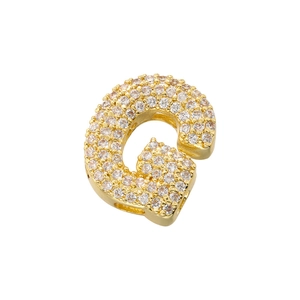 Macro detail of gold-plated letter G pendant with full cubic zirconia micro-inlays