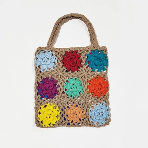 Detailed view of hand-crocheted colorful floral granny squares on a beige tote bag