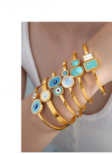 Macro detail of gold-plated titanium steel bangles with turquoise and shell inlay