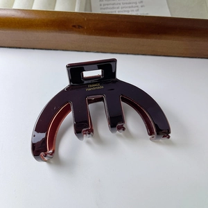Detail of a dark brown acetate hair claw clip showing the gold France Handmade logo