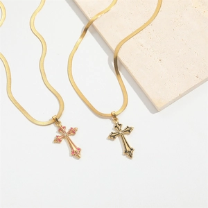 Gold cross necklaces with red and black accents on snake chains over marble stone