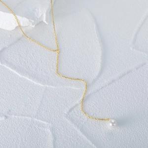 Macro shot of gold S925 sterling silver Y-shaped necklace with a single white pearl