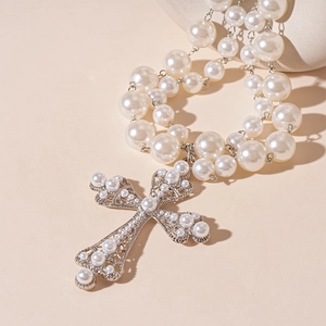 Close-up of double-layer faux pearl necklace with large silver cross pendant detail