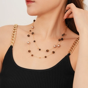 Detail of layered gold necklace with tiger eye stones and pearls on model neck