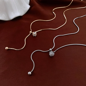 Detail of adjustable gold and silver snake chains with sliding toggle and round pendants