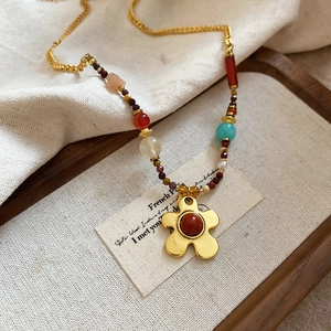 Detailed shot of retro gold flower necklace with red gemstone and colorful beads