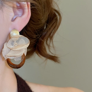 Detail of artistic floral earring with beige chiffon fabric and resin ring drop