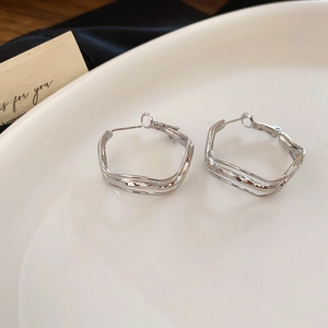 Macro view of silver wave irregular geometric earrings with a polished metallic finish