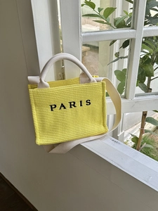 Fashionable yellow woven straw tote bag with long straps and Paris logo for beach vacations