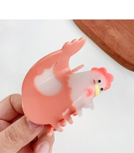 Close-up of pink and white acetate chicken hair claw clip held in hand for hair styling