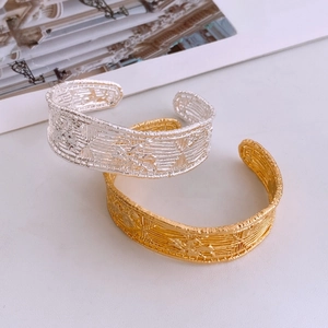 Close-up of vintage gold and silver open bangles with intricate woven texture detail