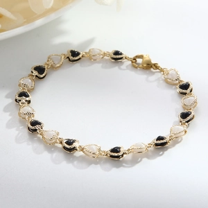 Close-up of gold heart-shaped bracelet with black and white enamel link details