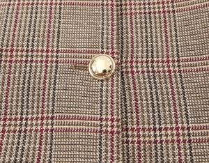 Detailed close-up of brown houndstooth fabric texture and a round gold metal button