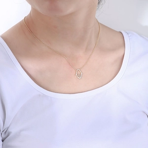 Detail of s925 silver gold Hamsa Hand necklace with zircons worn by a model