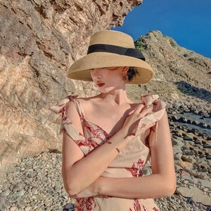 French style sun straw hat with black bow ribbon on beach background for summer vacation