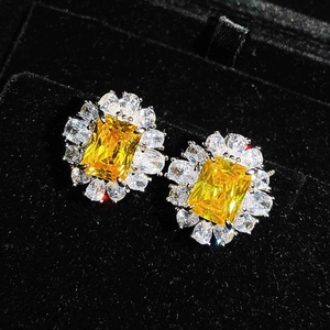 Detail of emerald cut yellow gemstones surrounded by pear shaped white zircon earrings