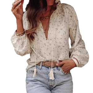 Detail of floral bohemian shirt featuring tassel ties, lace inserts, and lantern sleeves