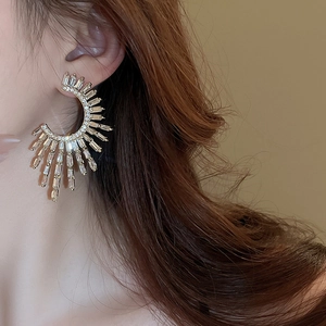 Close-up of model wearing gold C-shaped earrings with radiating rectangular cubic zirconia