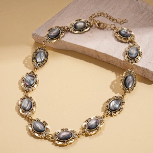 Detail view of retro gold oval resin necklace with dark grey iridescent stones