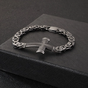 Detailed view of men's Byzantine chain bracelet with a textured cross on a black box