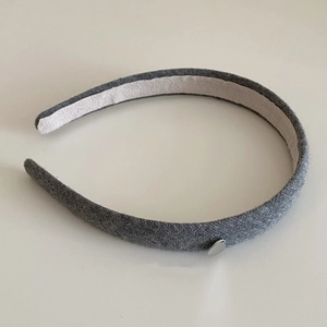 Détail d'un serre-tête en tricot gris avec un petit pendentif en métal en forme de cœur