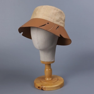Elegante cappello a secchiello in rafia con tesa in pelle e intagli su supporto espositivo