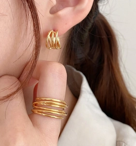 Macro view of gold minimalist woven multilayer earrings and matching stacked rings