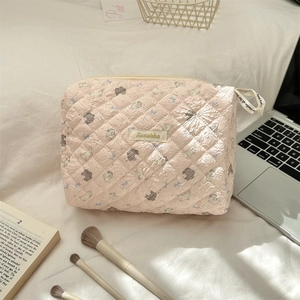 Detailed close-up of a pink quilted cosmetic bag featuring cute cartoon animal prints