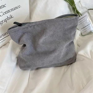 Close-up of a gray corduroy makeup bag with a top zipper on an aesthetic ins-style background