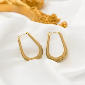 Macro view of gold spiral spring earrings with irregular texture on white silk fabric