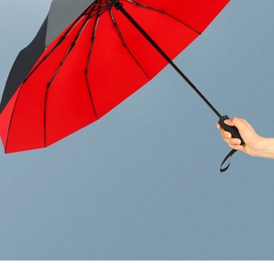 Detail of automatic folding umbrella with black exterior and vibrant red interior fabric