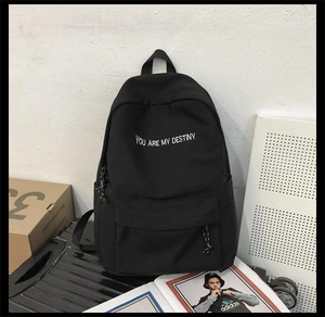 Détail d'un sac à dos noir avec broderie blanche du texte YOU ARE MY DESTINY