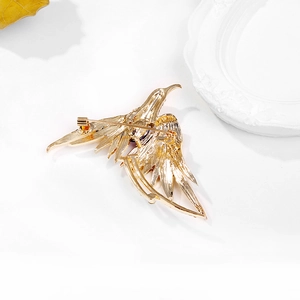 Macro detail of the golden metal phoenix brooch back showing pin clasp and fine texture
