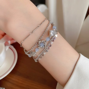 Close-up of layered silver bracelets with blue crystal beads on a female wrist