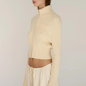 Detail of slim-fit ribbed crop sweater with zipper neck and decorative patch