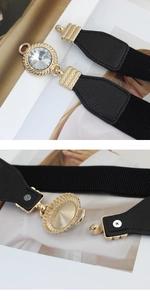 Detailed view of black elastic belt featuring a golden buckle with a large clear crystal
