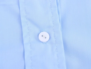 Vue rapprochée d'un bouton blanc et texture du tissu sur une chemise bleu clair