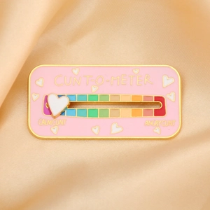 Close-up of pink enamel mood tracker pin with sliding heart on rainbow scale and gold edges