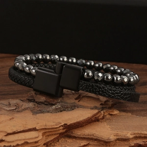 Macro detail of men's leather braided bracelet with grey beads and matte black magnetic clasp