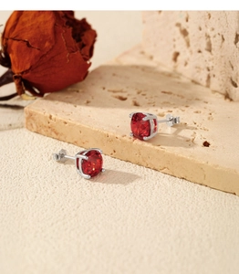 Macro shot of silver stud earrings with sparkling red gemstone in a classic four-prong setting
